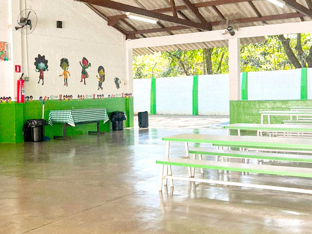 Mesas e bancos do refeitório do COC Tigrinho, no pátio coberto